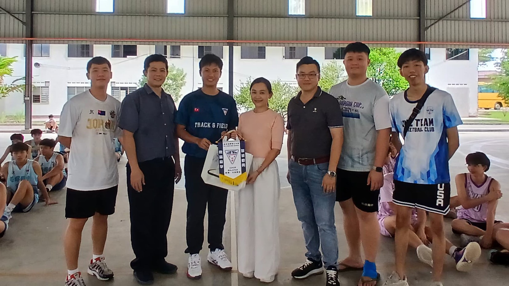 本校由体育处主任姚道达老师（左三）代表，赠送锦旗予拿督斯里哈芝阿曼国中（SDAHA），由家教协会理事董惠婷（右四）代表接领
