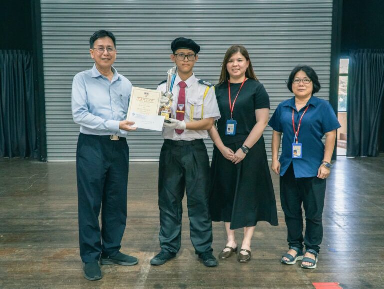 学长团曾文彬同学 拿下本届步操比赛 “全场最佳司令员” 奖项，由王楨文校长（左一）颁发奖金、奖状与奖杯，同时由评审 黄金施主任、与沈欣蕾副校长陪同见证